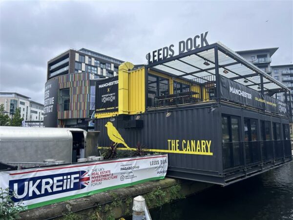 Sign 'Leeds Dock' above an outdoor space in the dockyard of UKREiif