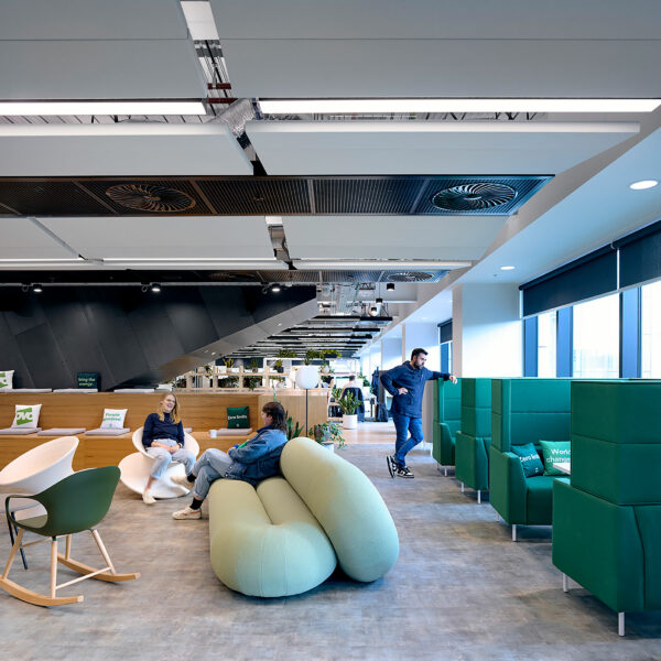 Different types of furniture including rocking chairs and a funky sofa with the stairwell behind and booths on the right side