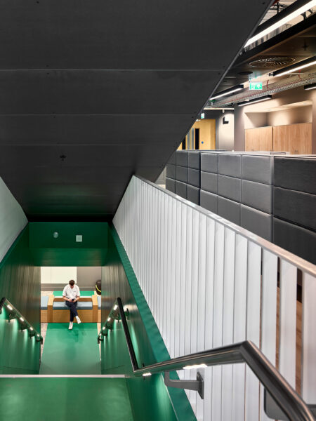 Entrance to a staircase descending to the next floor where someone is sitting on a bench