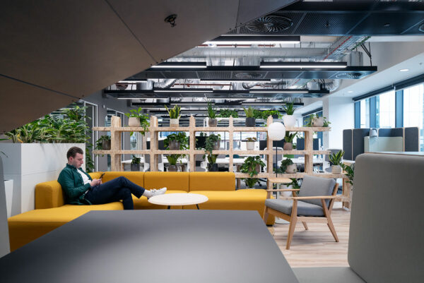 Man sitting on yellow sofa with office behind