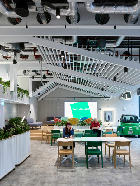 Event space with small green branded car on one side and table and chairs in front