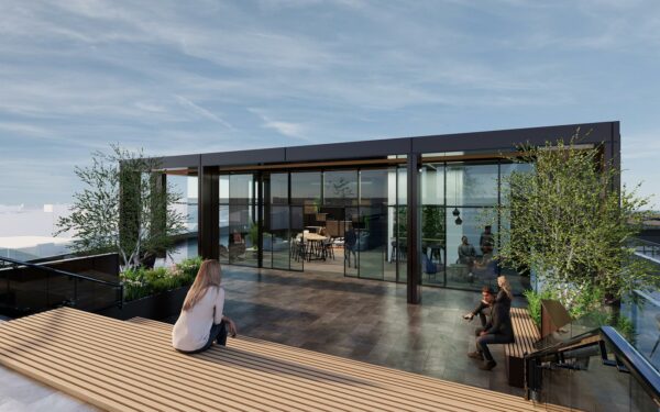 Woman sitting on decking on an office roof terrace with view to the glass walled indoor space