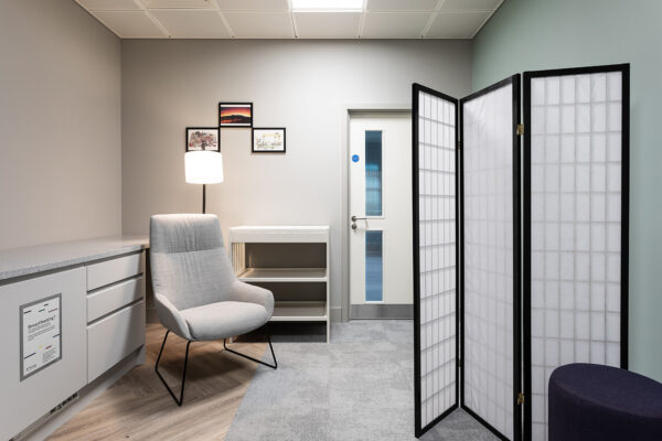 Comfortable armchair on left side with baby changing table behind and privacy screen in front.