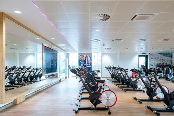 Indoor gym class space with rows of stationery cycling bikes.