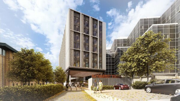 Exterior of building displaying floor to ceiling windows in apartments divided between a stone wall. On site parking is available outside.