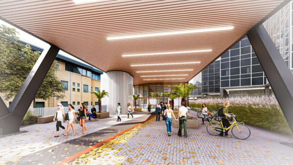 Large wooden canopy entrance overhead. Greenery surrounding the structure and many bike parking stations alongside.