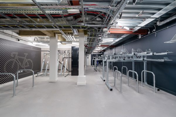 A room for bikes to be stored and kept with dark grey walls and contrasting light grey flooring.
