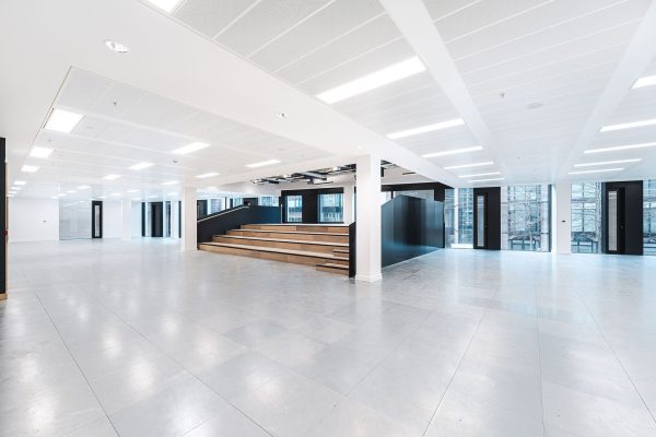 A bright space with white walls and floor, with contrasting black details at doors and stairs.
